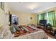 Bedroom with yellow walls, a bed with a colorful blanket, and windows with green curtains at 114 S Gunlock Ave, Tampa, FL 33609