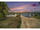 Inviting single-story home with a two-car garage, complemented by lush landscaping and a colorful sunset backdrop at 13614 Evelane Dr, Hudson, FL 34667