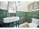 Stylish powder room featuring green tiled walls, a modern vessel sink, and unique artwork at 3390 W Maritana Dr # 4, St Pete Beach, FL 33706