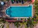 Aerial view of a refreshing in-ground pool surrounded by lush tropical landscaping and patio furniture for relaxation at 3390 W Maritana Dr # 4, St Pete Beach, FL 33706