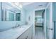 Light and airy bathroom featuring a marble vanity, decorative mirror, and view into the main bedroom at 5130 Brittany S Dr # 201, St Petersburg, FL 33715