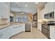 Well-lit kitchen with white cabinets, stainless steel appliances, and a view into the open-concept living area at 7115 Nightshade Dr, Riverview, FL 33578