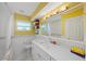Bright bathroom showcasing yellow walls, white cabinets, marble countertops, and a framed vanity mirror at 9911 Antilles Dr, Seminole, FL 33776