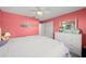Cozy bedroom features salmon walls, white ceiling fan, and beach-themed decorative prints above the bed at 9911 Antilles Dr, Seminole, FL 33776