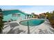 Backyard pool and turquoise home with a covered pergola and lush landscaping, perfect for outdoor relaxation at 9911 Antilles Dr, Seminole, FL 33776