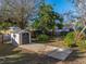 Spacious backyard featuring a large shed with a concrete path, mature trees, and partial fencing at 1213 60Th S St, Gulfport, FL 33707