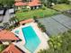 Aerial view of a community showcasing a pool, tennis courts, lush landscaping, and red tiled roofs at 1003 Hammock Pine Blvd # 1003, Clearwater, FL 33761