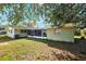 Rear view of a home featuring a screened-in porch and mature trees, offering a serene outdoor living space at 2713 W Osborne Ave, Tampa, FL 33614