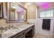Bathroom featuring marble countertop vanity, a large mirror, and a shower with pink neon sign at 2713 W Osborne Ave, Tampa, FL 33614