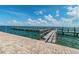 Expansive wooden dock extending into the tranquil blue water under a sunny sky with scattered white clouds at 4744 Snook Se Dr, St Petersburg, FL 33705