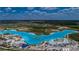 An aerial view of a Primary-planned community's vibrant lagoon and beachfront area with slides, beach chairs and recreation at 7580 Pool Compass Loop, Wesley Chapel, FL 33545