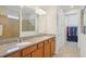 Bathroom features double vanity with granite countertops and wood cabinetry, with a walk-in closet at 7580 Pool Compass Loop, Wesley Chapel, FL 33545
