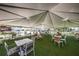Large outdoor event space under a tented roof with multiple tables and chairs set up on an artificial turf lawn at 7580 Pool Compass Loop, Wesley Chapel, FL 33545