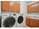 Laundry room featuring newer washer and dryer and wood cabinets at 7580 Pool Compass Loop, Wesley Chapel, FL 33545