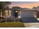 Charming single-story home featuring a well-maintained lawn, brick walkway and a two car garage at sunset at 8315 Moccasin Trail Dr, Riverview, FL 33578