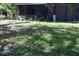 Grassy backyard with a screened lanai, plants, and a shady tree at 11723 Raintree Village Blvd # B, Temple Terrace, FL 33617