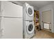 Functional laundry area with a stacked washer/dryer set, shelving, and access to the backyard at 2016 Culberson Ave, Dunedin, FL 34698