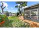 Side view of backyard featuring a landscaped lawn, shed, barbecue, and access to the screened patio at 2940 Bay View Dr, Safety Harbor, FL 34695