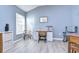 Bright home office with wood-look floors, a large window, desk, and comfortable seating at 31841 Larkenheath Dr, Wesley Chapel, FL 33543