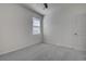 An empty bedroom featuring light carpet, a ceiling fan, and a large window with bright natural light at 3624 Autumn Amber Dr, Spring Hill, FL 34609
