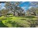 Expansive backyard with lush green lawn, mature trees providing shade, and a screened-in porch for outdoor living at 4110 Highland Park Cir, Lutz, FL 33558