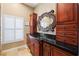 Bathroom vanity with wood cabinets, black granite countertop, a large mirror, and a window with shutters at 4110 Highland Park Cir, Lutz, FL 33558