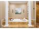 Luxurious bathroom featuring a soaking tub framed by decorative pillars and travertine tile at 4110 Highland Park Cir, Lutz, FL 33558