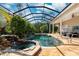 Inviting screened pool and spa area with waterfall feature and lush tropical landscaping at 4110 Highland Park Cir, Lutz, FL 33558