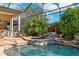 Beautiful screened pool area featuring a rock waterfall and lush, tropical landscaping at 4110 Highland Park Cir, Lutz, FL 33558