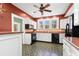 Charming kitchen featuring bright red walls, vintage tiled floors, white cabinets, and modern black appliances at 6935 Date Palm S Ave, St Petersburg, FL 33707
