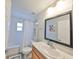 Bathroom featuring a shower, commode, vanity with sink, and large mirror at 7325 S Trask St, Tampa, FL 33616