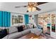 Cozy living room featuring a comfortable gray sectional sofa, ceiling fan, and sliding glass doors to the patio at 7820 Pineapple Ln, Port Richey, FL 34668