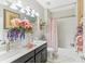 Bathroom featuring a double vanity, decorative mirror, tub and shower with pink floral accents at 13218 Satin Lily Dr, Riverview, FL 33579