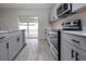 Modern kitchen with stainless steel appliances, gray cabinets and a view to the backyard at 13106 Zolo Springs Cir, Riverview, FL 33579