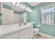 Bright bathroom featuring teal walls, white vanity, decorative lighting, and a large mirror, creating a fresh and inviting space at 13216 Parkhurst Ct, Riverview, FL 33569