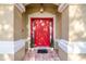 Inviting entryway with a bright red door, sidelights, and decorative plants flanking the entrance at 5913 Lawrin Ct, Wesley Chapel, FL 33544