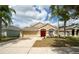 Single-story home featuring a manicured lawn, a bright red front door, and an attached two-car garage at 5913 Lawrin Ct, Wesley Chapel, FL 33544