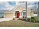 Charming single-story home with a red front door, a manicured lawn, and an attached two-car garage at 5913 Lawrin Ct, Wesley Chapel, FL 33544