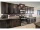 Modern kitchen with dark wood cabinets, stainless steel appliances, and sleek countertops at 11717 Navajo Sandstone St, Riverview, FL 33579