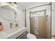 Bathroom featuring modern vanity, gold hardware, a round mirror, and a tiled shower with a glass block window at 2301 46Th S St, St Petersburg, FL 33711