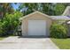 Spacious detached garage with a single white door, set amongst lush greenery and a concrete driveway at 2301 46Th S St, St Petersburg, FL 33711