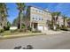 Tan townhome with a two-car garage, mature palm trees, and manicured lawn at 2967 Bayshore Pointe Dr, Tampa, FL 33611
