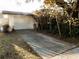 View of single story home with white garage door and partial driveway showing mature landscaping at 528 Manor Dr, Dunedin, FL 34698