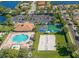 An aerial view of community pool, tennis court, volley ball court and parking, surrounded by lush landscaping at 9003 Willowbrook Cir, Bradenton, FL 34212