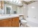 Bathroom features a tub with tiled walls, oak vanity, and decorative wallpaper at 11018 Courtland St, Trinity, FL 34655