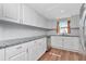 Beautiful white kitchen with stainless steel dishwasher, granite countertop, and wood grain flooring at 1350 Brixton Ln, Holiday, FL 34691