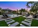 Beautiful backyard with a modern pool, lounge chairs, fire pit and lush, green lawn and a tropical landscaping at 5004 S The Riviera, Tampa, FL 33609
