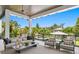 Spacious covered outdoor seating area featuring a plush sofa, chairs, and views of a pool and lush landscaping at 5004 S The Riviera, Tampa, FL 33609