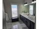 Modern bathroom featuring dual vanities, sleek fixtures, and a bright window for natural light at 6601 Thackston Dr, Riverview, FL 33578