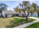 Charming single-story home with manicured lawn, mature trees, and inviting walkway, offering curb appeal and a sense of tranquility at 2893 Turtle Ter, Palm Harbor, FL 34683